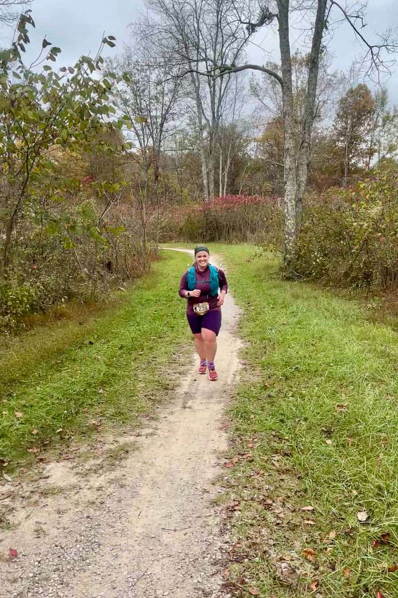 Woman running on dirt trail to participate in Mammoth Cave 25K race.