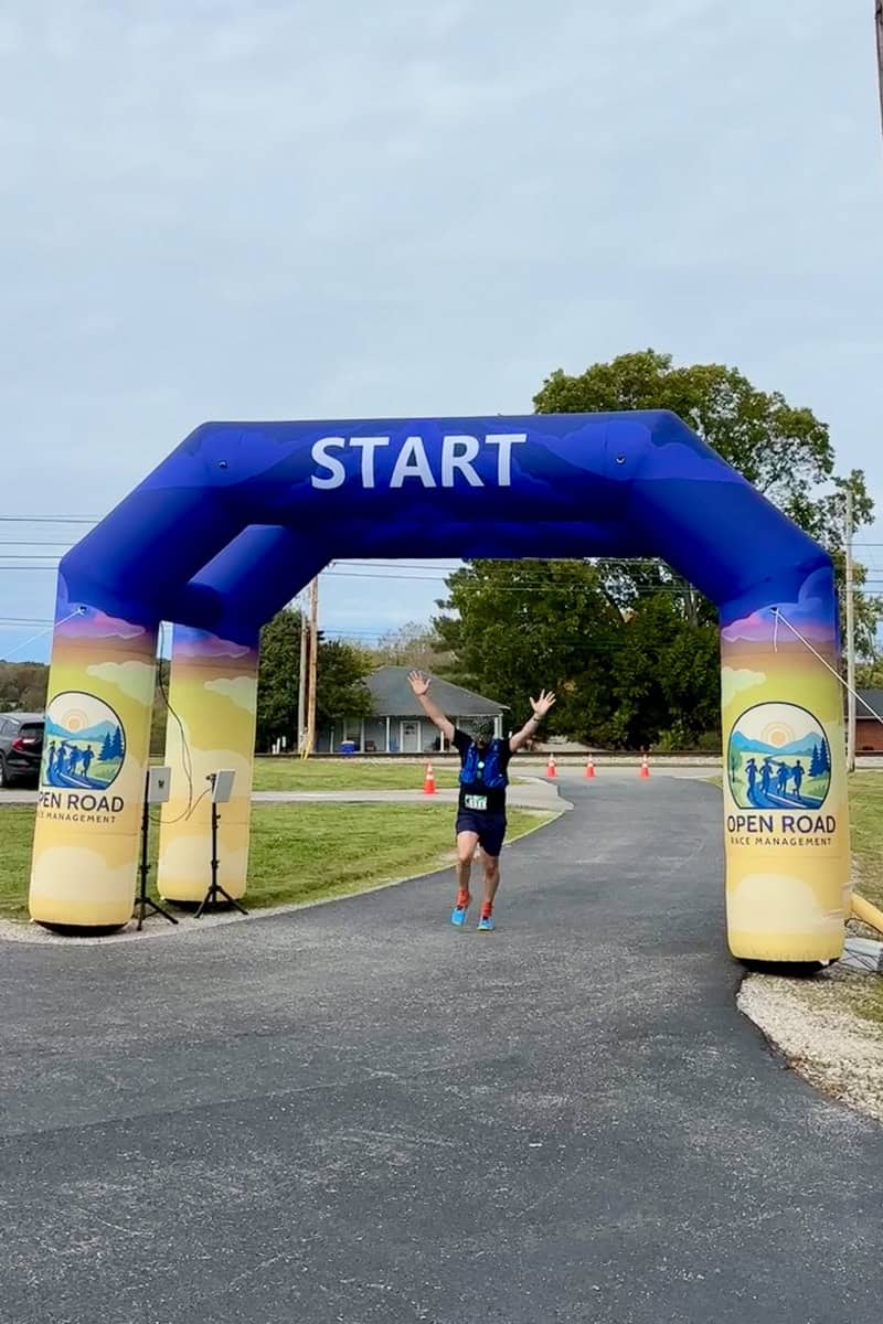 Man crossing finish line at completion of 50K race.