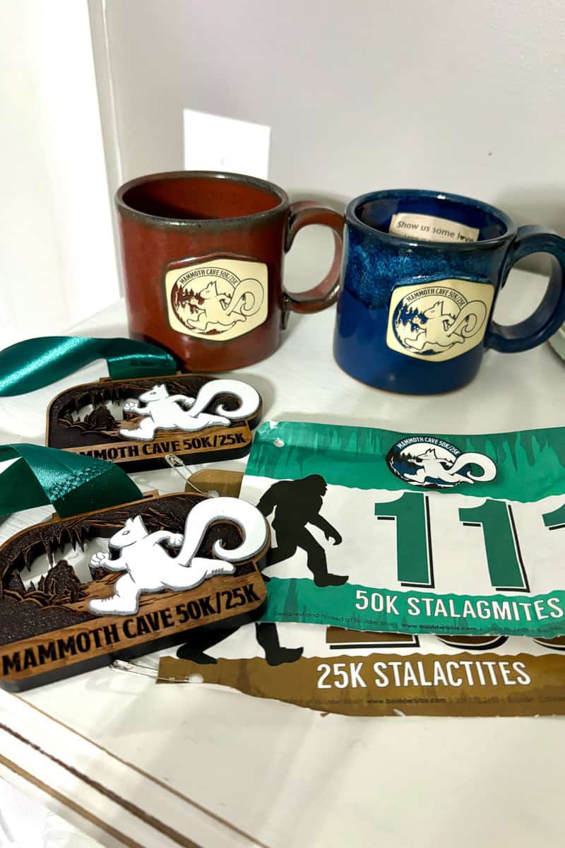 Ceramic mugs, finisher medals, and bibs, all branded for Mammoth Cave Race.