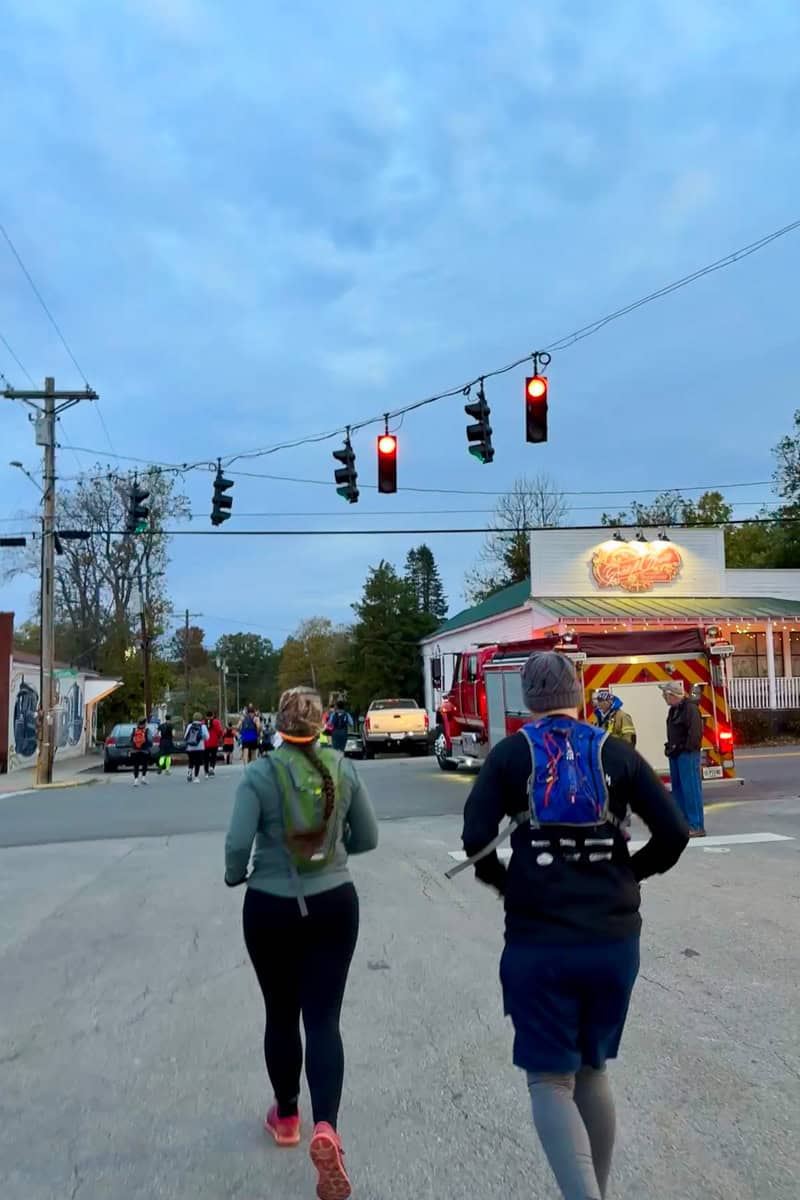 Runners cross street at traffic light intersection.