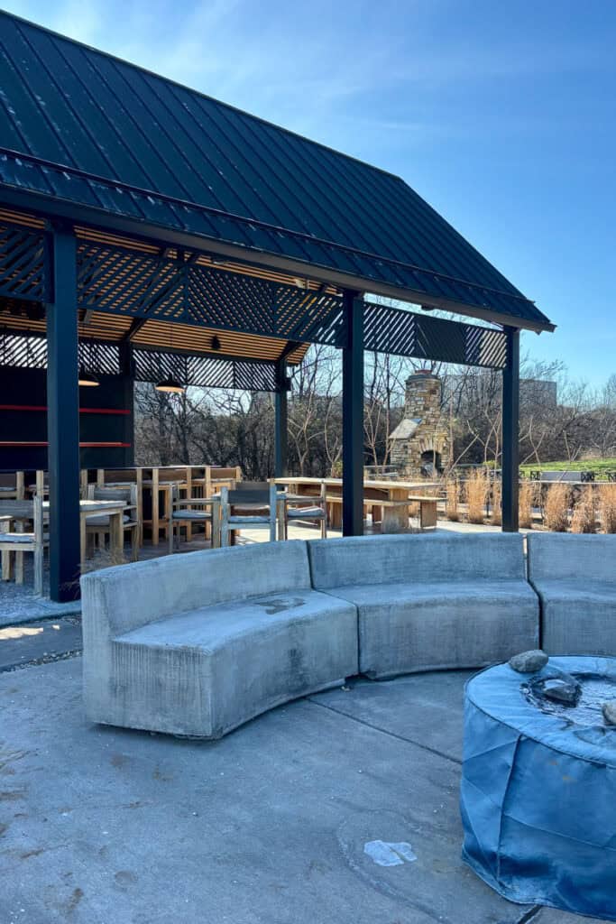 Concrete benches and wooden tables in outdoor lounge area.