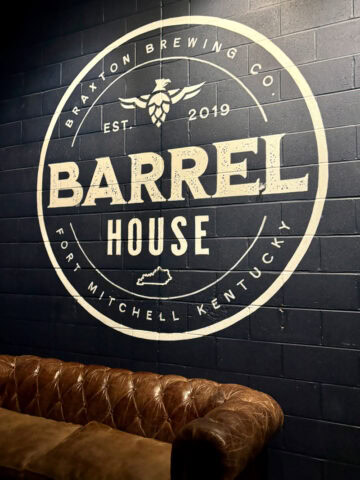 Braxton Brewing Barrel House logo printed on interior black block wall of restaurant.