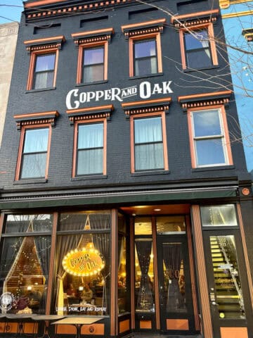 Exterior of Copper and Oak restaurant, a tall brick building painted black.