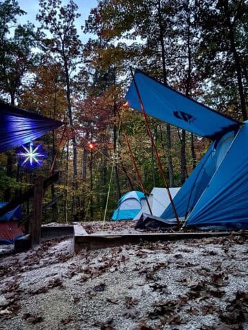 Group campsite with multiple tents set up and a star-shaped lantern suspended from canopy.