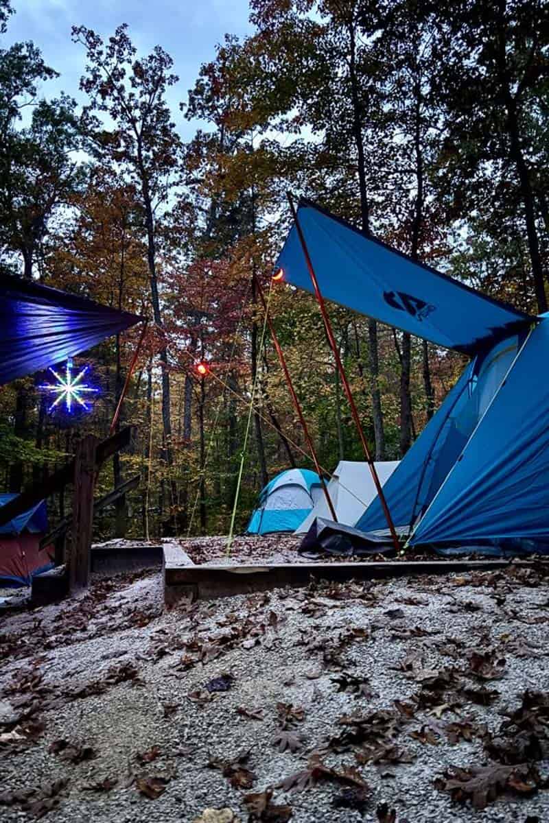 Group campsite with multiple tents set up and a star-shaped lantern suspended from canopy.
