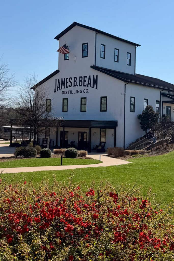 Exterior of Jim Beam Distillery, a white 3-story building with black trim.