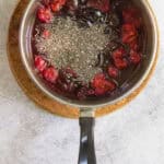 Chia seeds and lemon juice added to fruit mixture in saucepan.