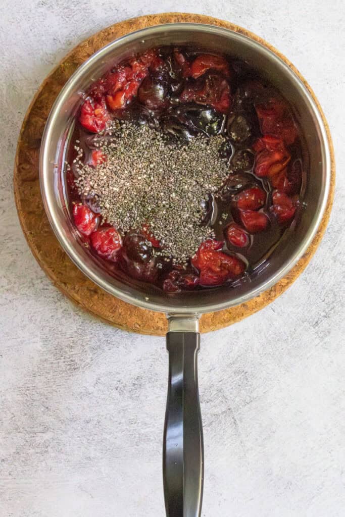 Chia seeds and lemon juice added to fruit mixture in saucepan.