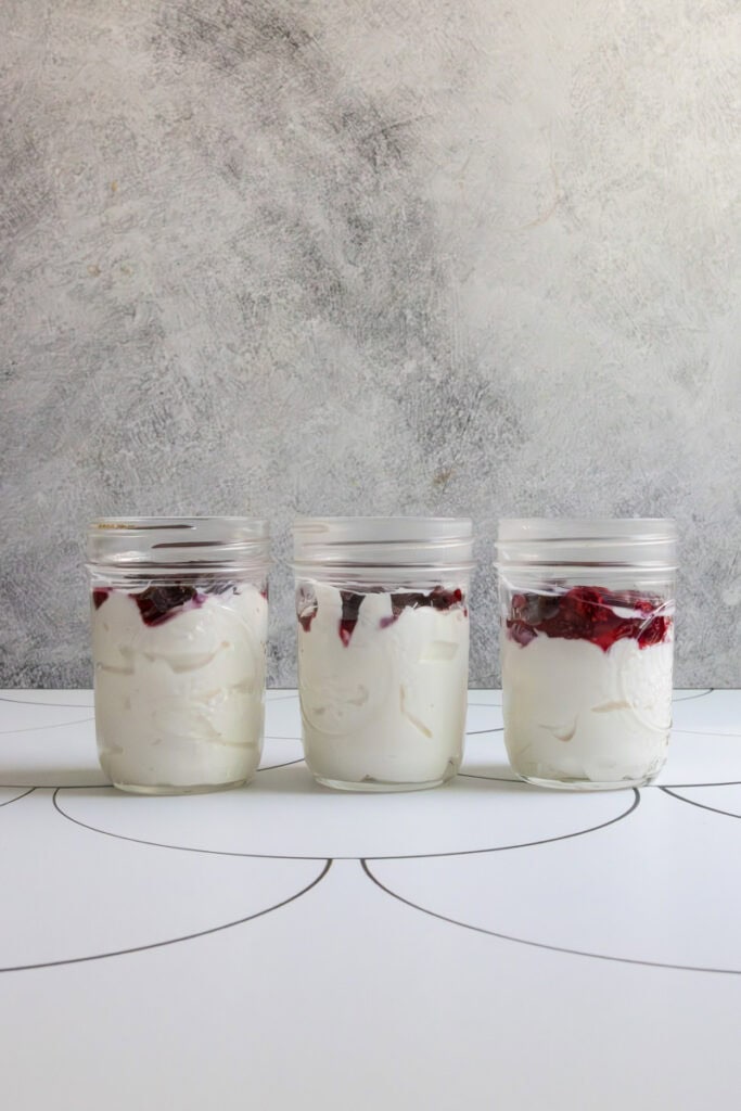 Jars layered with yogurt and fruit compote to make chia seed parfait.