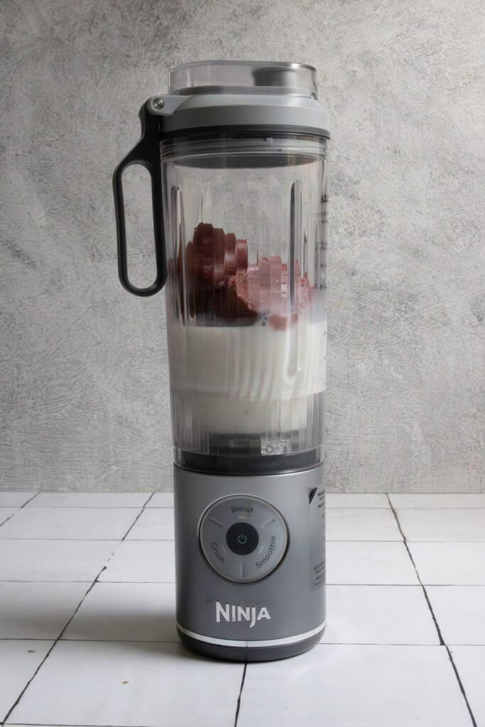 Chocolate cherry smoothie cubes in blender with milk.