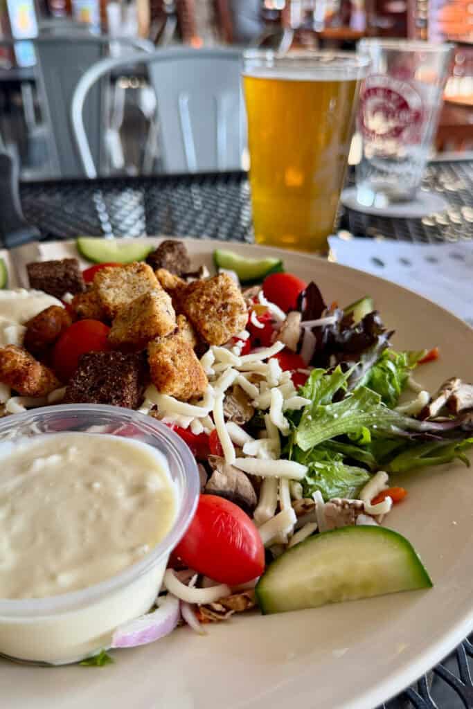 Salad with tomatoes, shredded cheese, croutons, and dressing on the side.