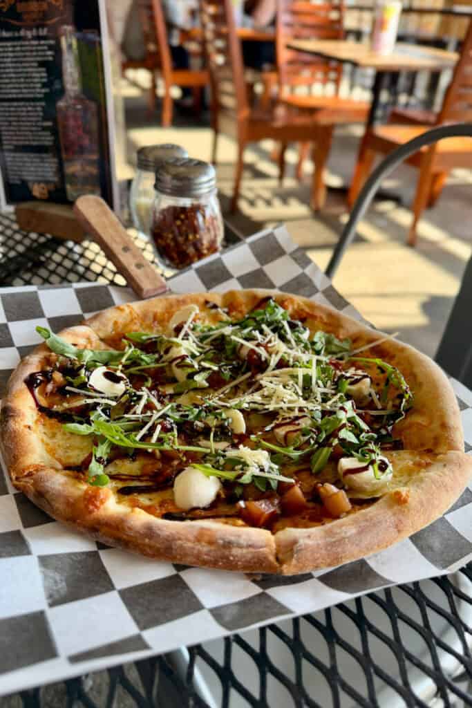Caprese pizza with arugula and balsamic drizzle.