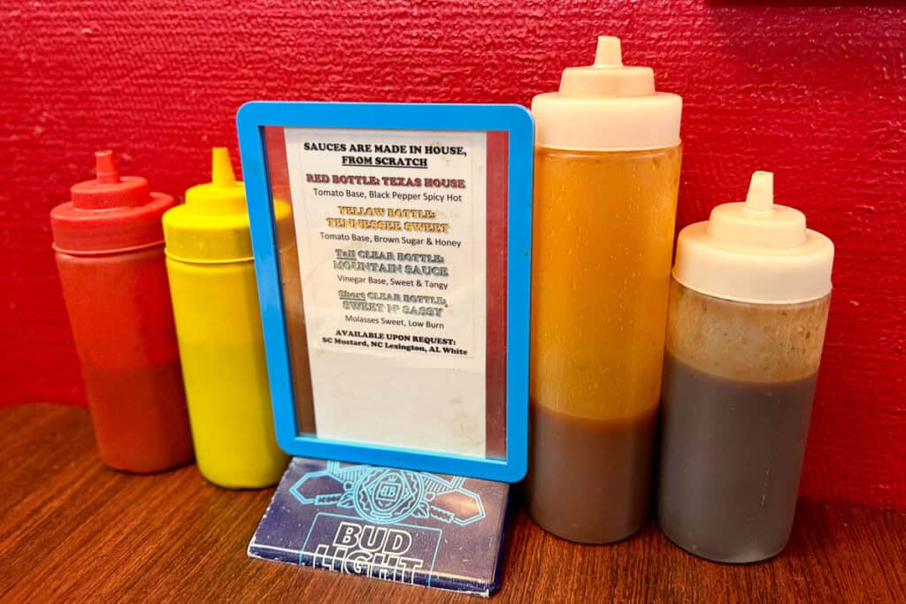 Four bottles of sauce with sign identifying each.