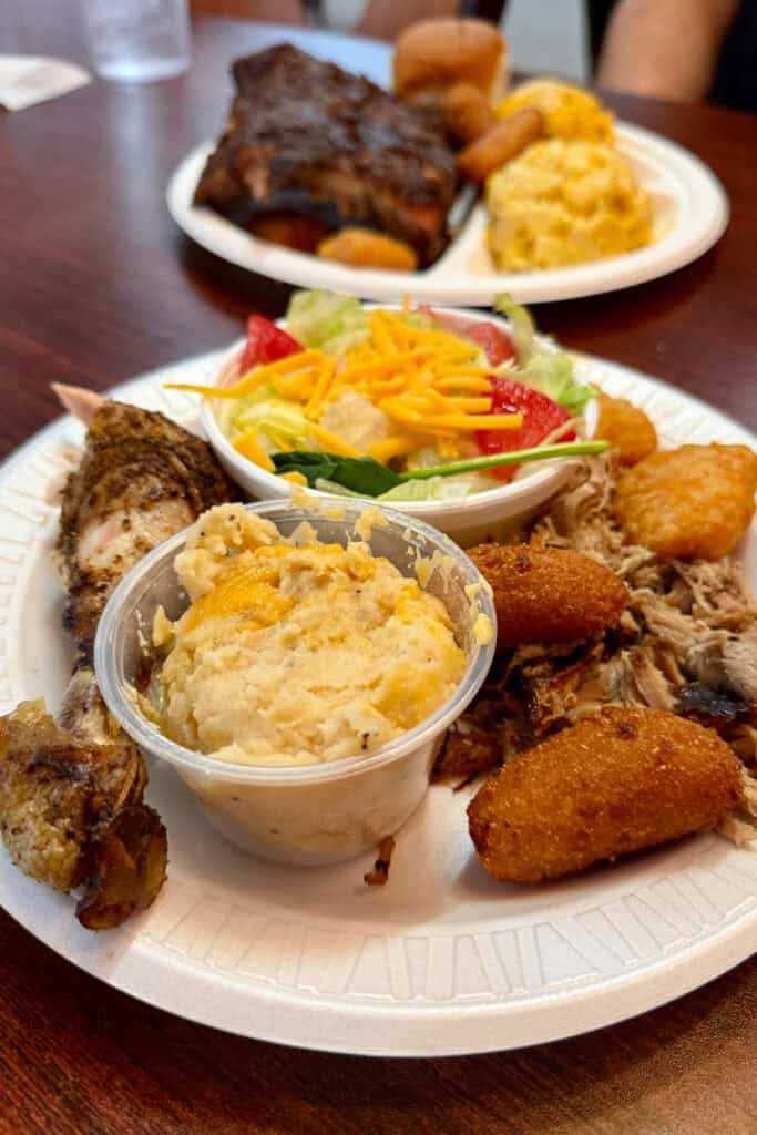 Platter with chicken and pork, mashed potatoes, and salad.