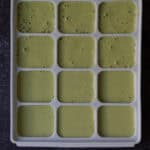 Green smoothie mixture poured into silicone molds.