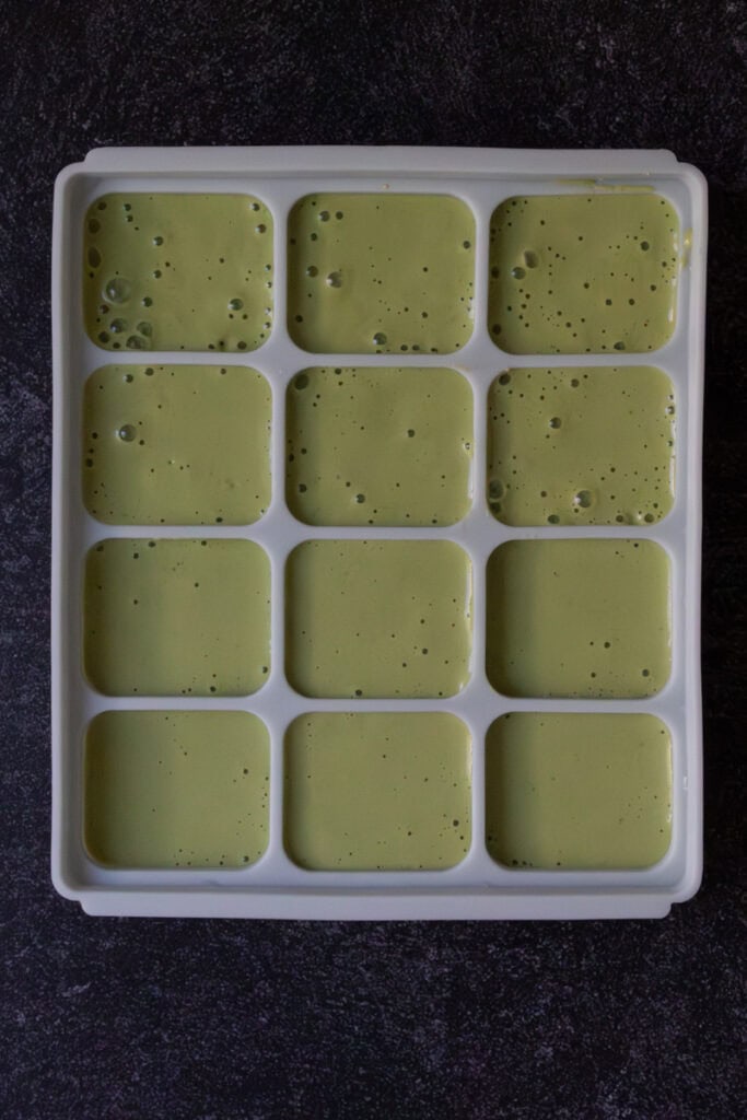 Green smoothie mixture poured into silicone molds.
