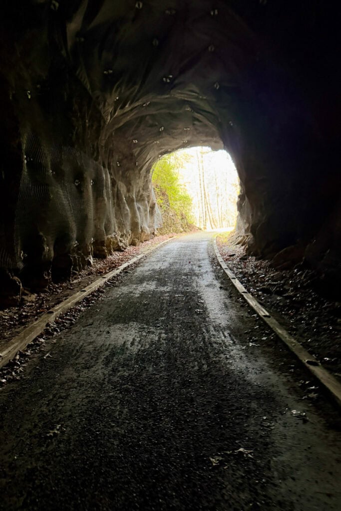 Gravel path through short rock-hewn tunnel.