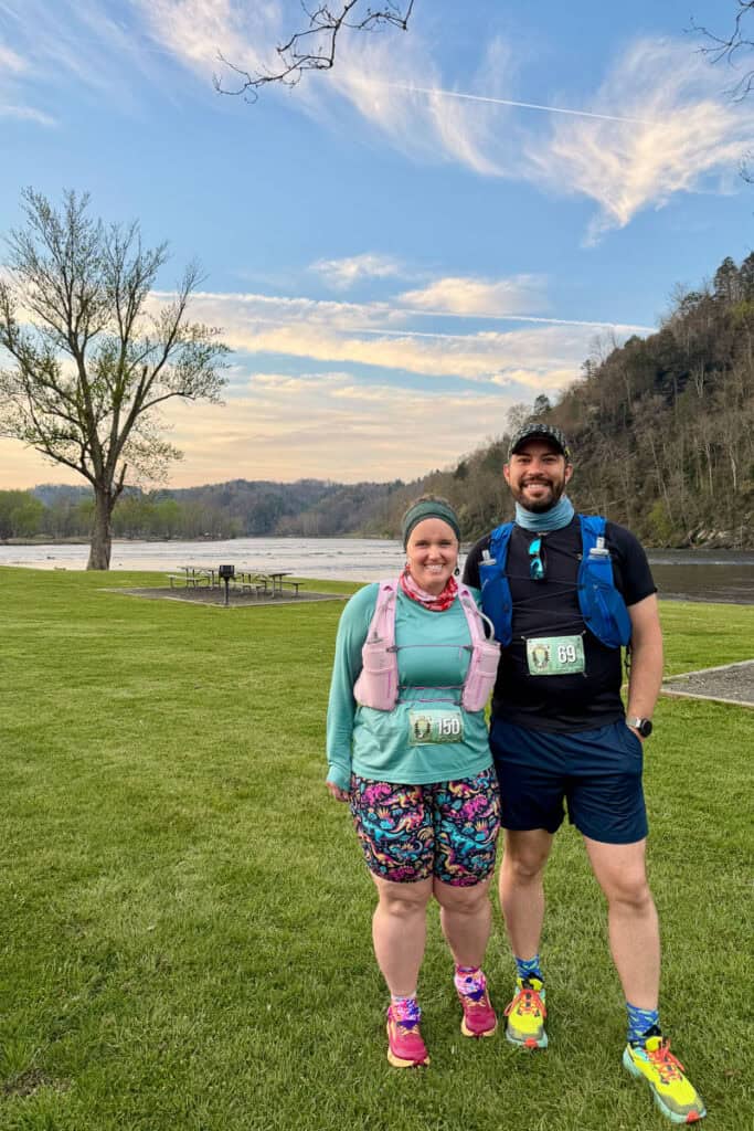 Man and woman in running gear for the New River Races with river and morning light in background.