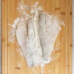 Fish fillets dusted with flour on cutting board.