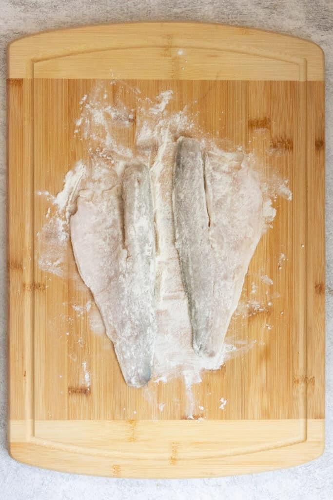 Fish fillets dusted with flour on cutting board.