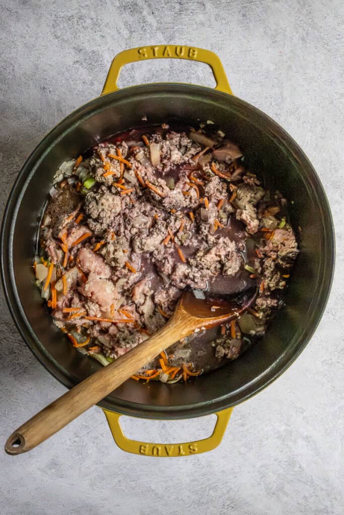 Sausage and ground turkey added to cooked vegetables in skillet.