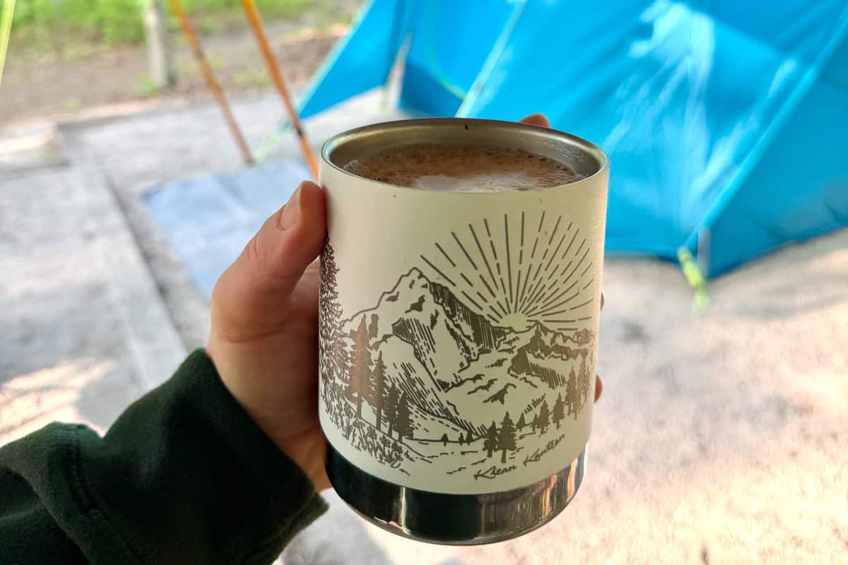 Mug of coffee with campsite in background.