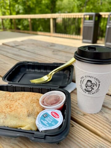 Crepe with sour cream and salsa next to cup of coffee.