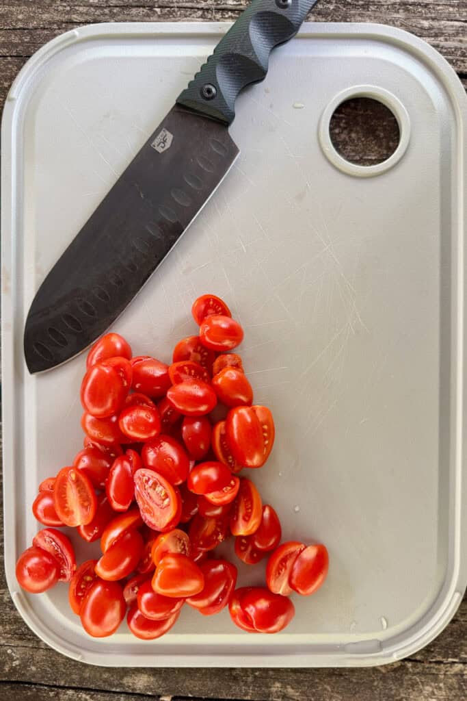 Knife and sliced tomatoes on cutting board.