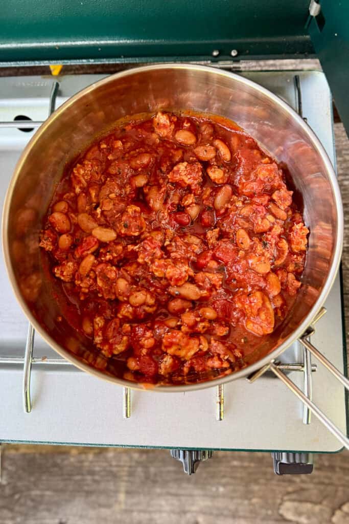 Meat, beans and tomatoes in saucepan.