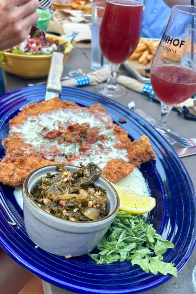 Plate of schnitzel served with cooked greens.
