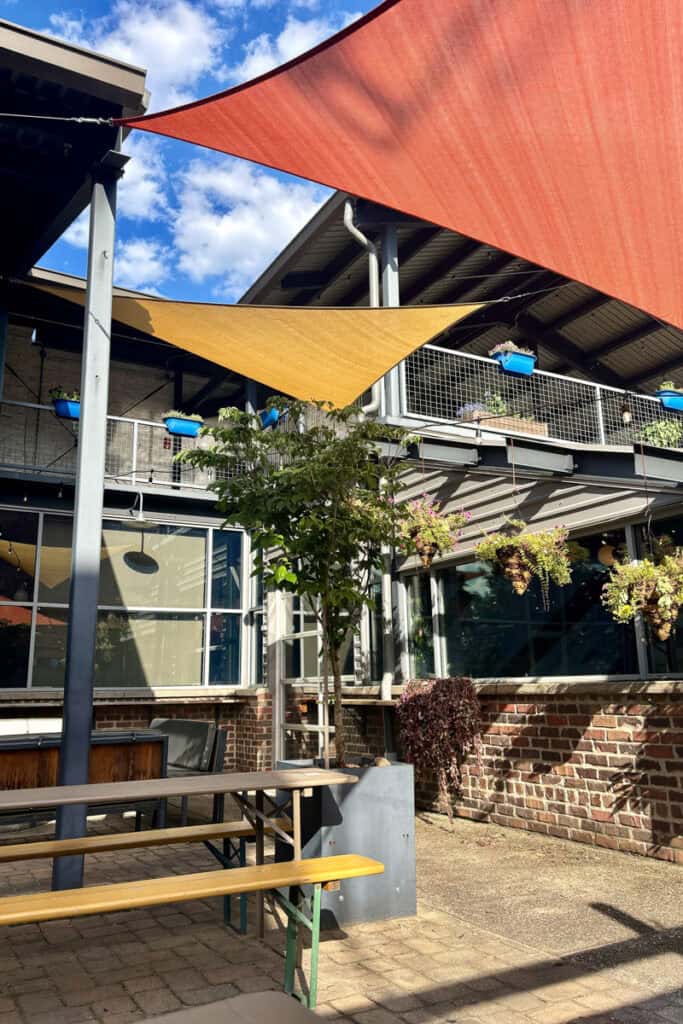 Picnic tables with canvas shades stretched across courtyard.