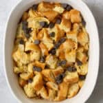 Pieces of croissant in casserole dish with chocolate chips sprinkled in.
