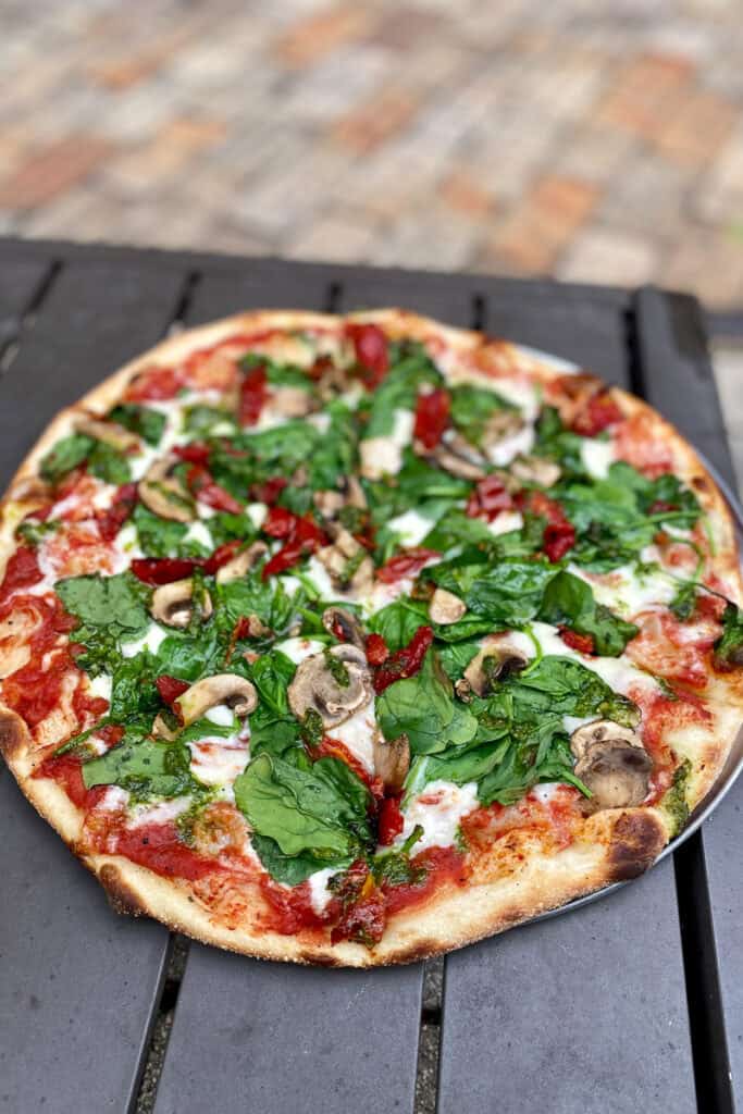The Bootlegger Pizza with spinach, mushrooms, tomatoes, and pesto.
