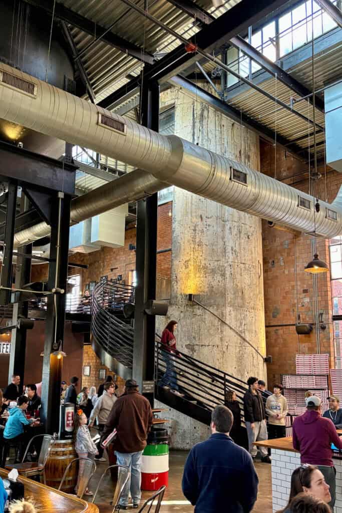 Busy indoor seating area at Goodfellas with staircase spiraling around old grain silo to upper seating area.