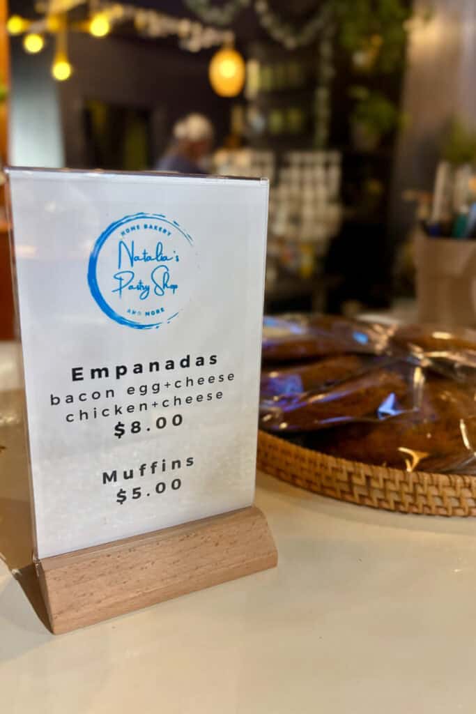 Sign listing empanadas and muffins for sale.