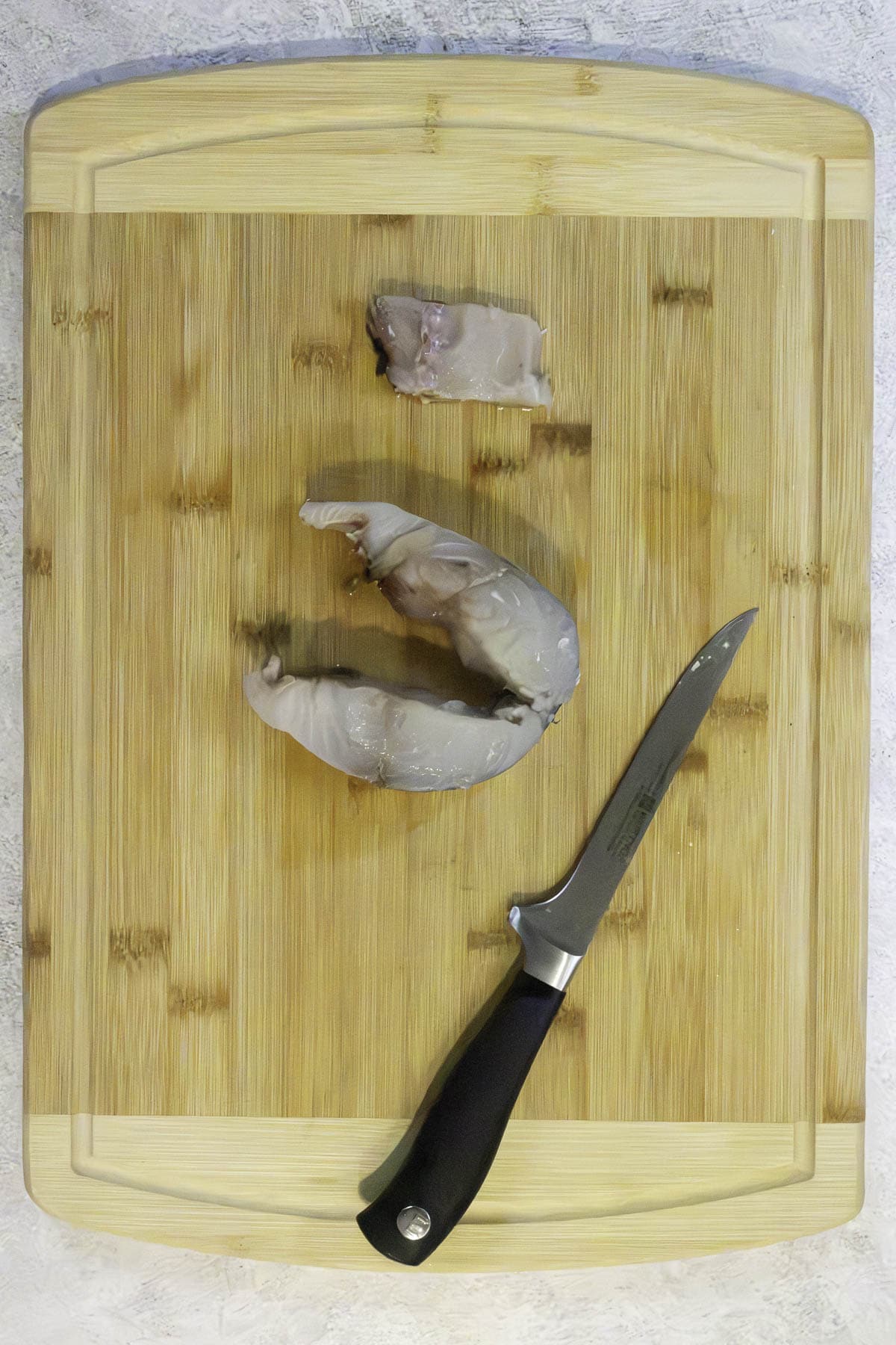 uncooked mackerel steak being deboned.