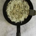 pulling the side of the potato pancake up with a spatula.