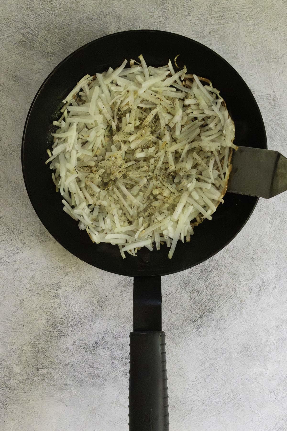 pulling the side of the potato pancake up with a spatula.