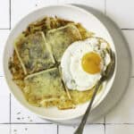 potato rosti with melted raclette and an egg on a plate.