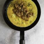 eggs topped with salmon in omelette pan.