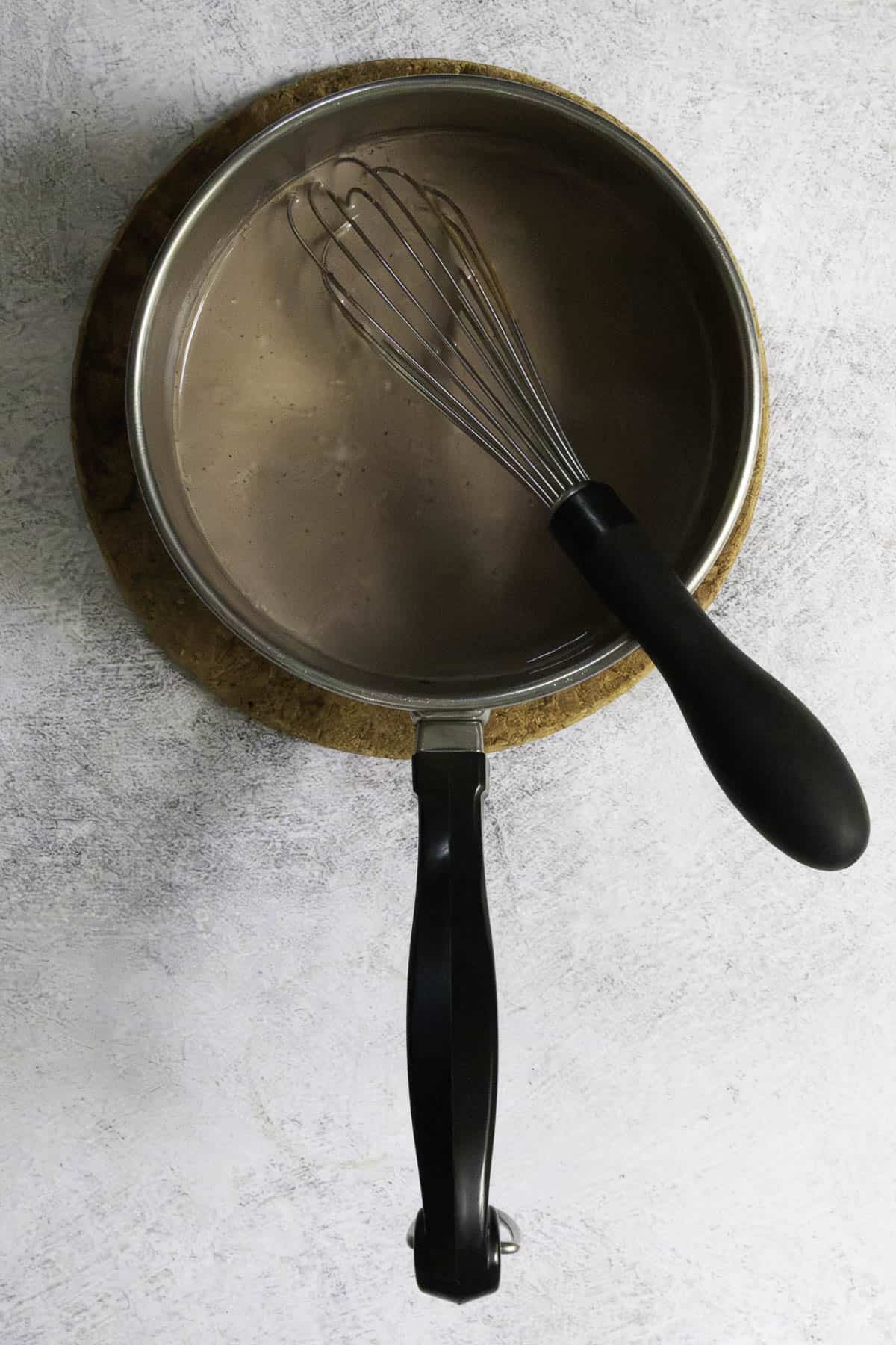 Hot chocolate mix stirred into warm milk in saucepan.