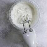 Blender resting on edge of bowl with newly whipped cream.