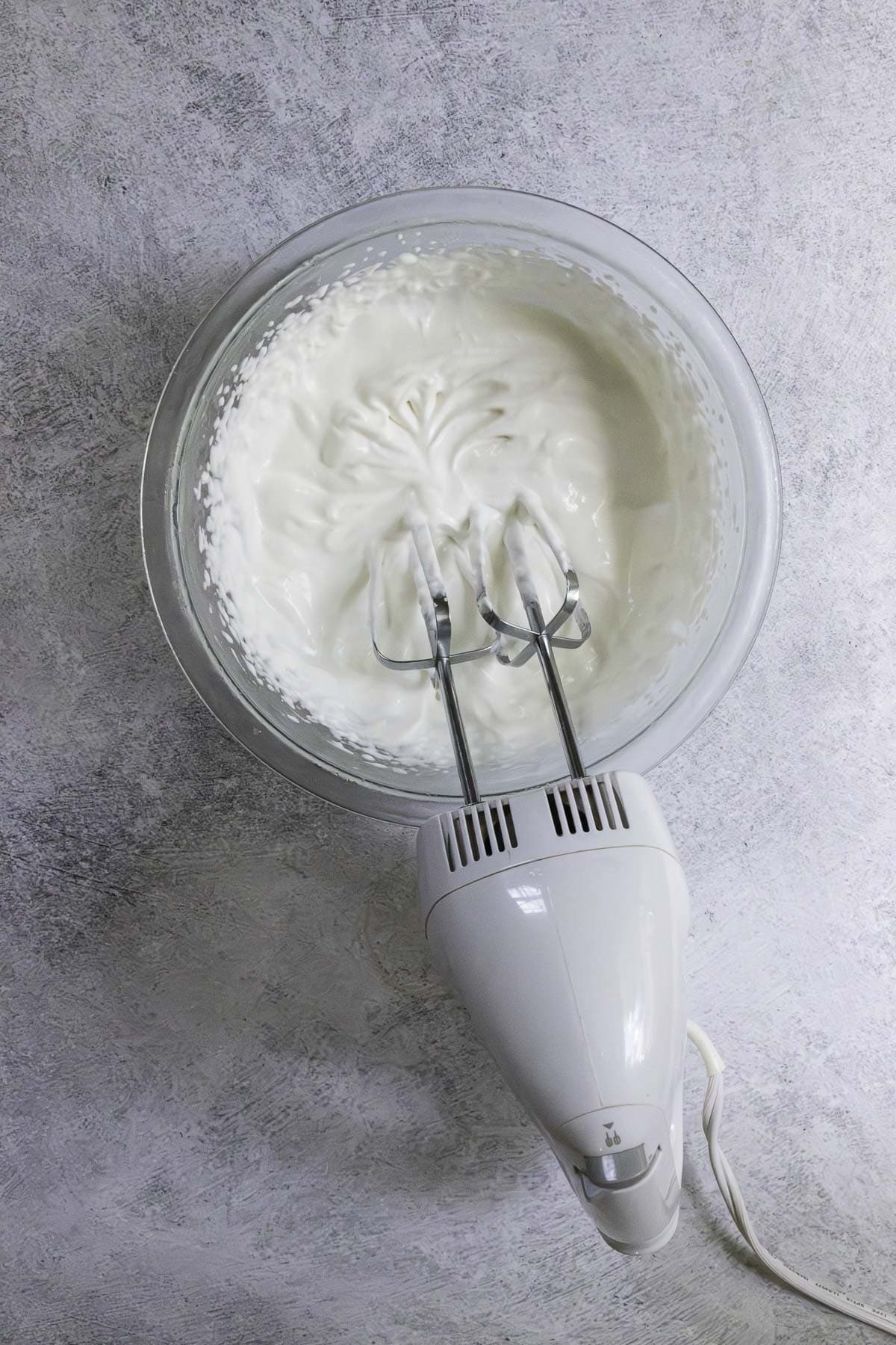 Blender resting on edge of bowl with newly whipped cream.