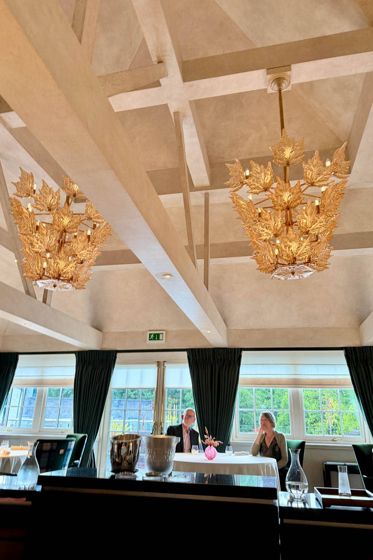 Dining room in Lalique at Glenturret restaurant, with two elegant chandeliers with leaf motif.